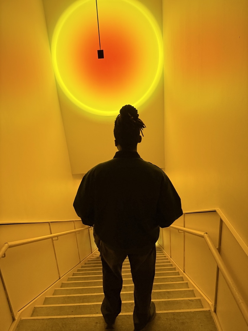Ikechukwu seen from behind on a stairwell under a glowing circle of light.